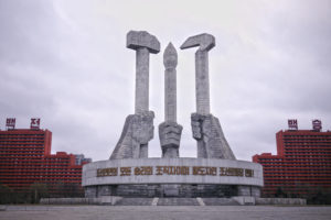 The iconic North Korea Worker’s Party Monument in Pyongyang, DPRK, represents the three pillars of the Revolution: Workers (hammer), Farmers (sickle), and Intellectuals (brush). The slogan says: “The organizers of the victory of the Korean people and the leader of the Workers Party of Korea